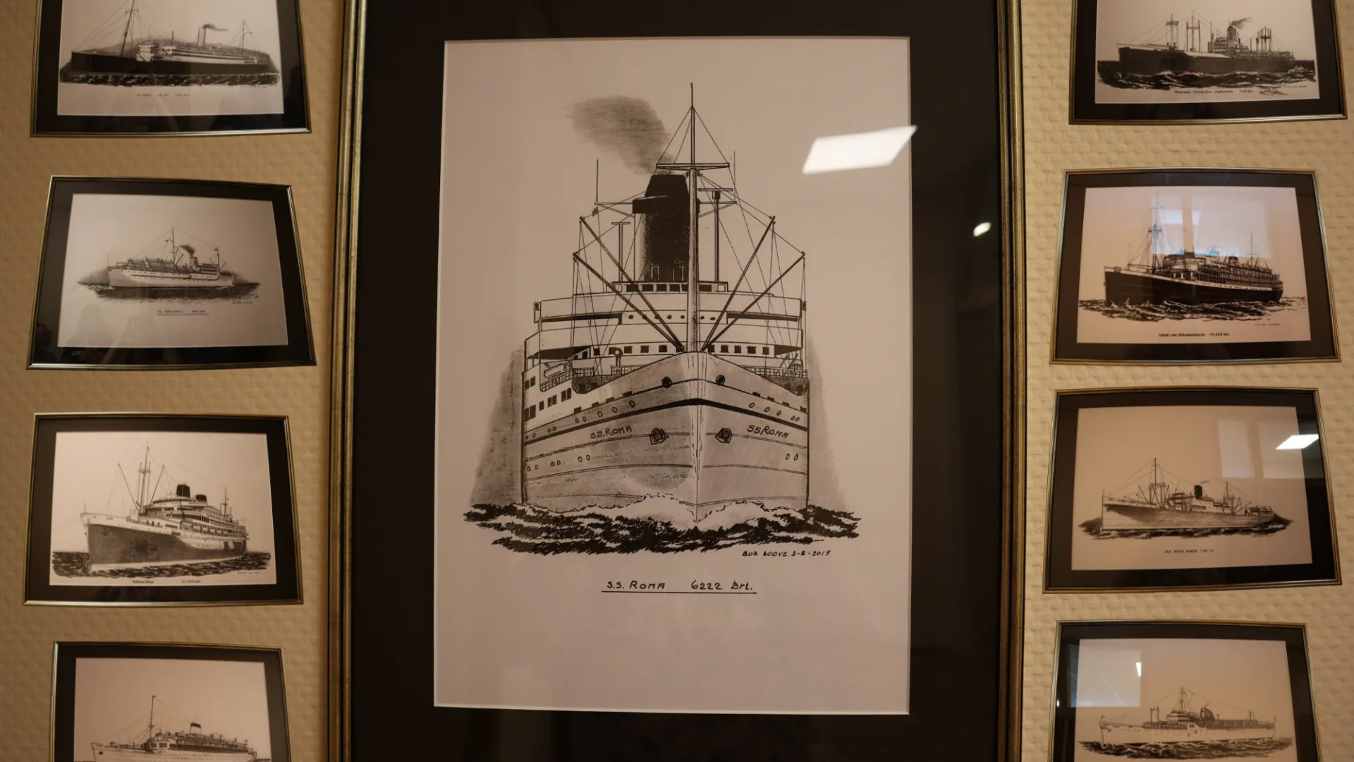 Ingelijste foto's van historische schepen aan de muur.
